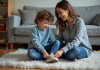 Gentillesse envers les enfants : comment la décrire avec justesse ? Jeune garçon assis sur un tapis de salon avec une femme qui lui noue les chaussures